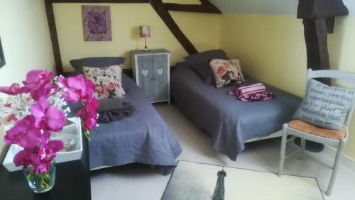 a room with two beds and a couch and flowers at La Gerbaudiere Chambres&Table d hotes proche Mont Saint Michel CUISINE MAISON in Notre-Dame-du-Touchet