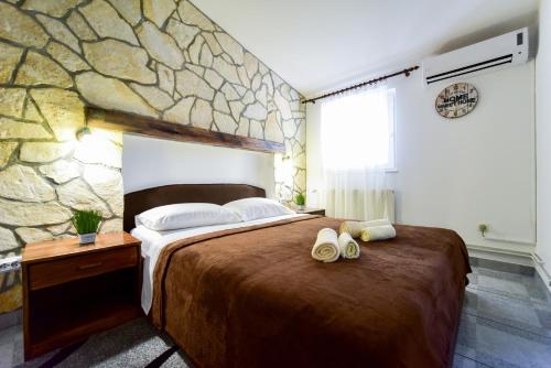 - une chambre avec un grand lit et un mur en pierre dans l'établissement Haus Josipa, à Maslenica