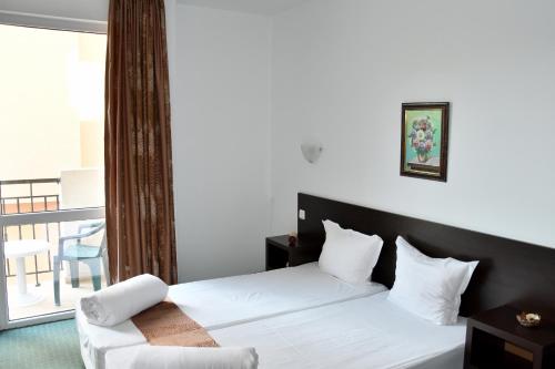 a bedroom with a white bed and a balcony at Family нouse -Нotel Asai in Ravda