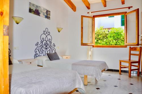 a bedroom with two beds and a window at Villa Na y Veni in Cala en Bosc