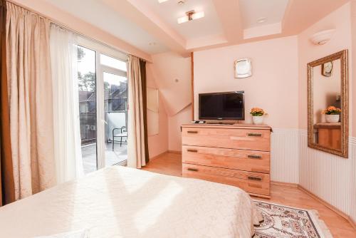 a bedroom with a bed and a tv and a dresser at Saulės Krantas in Palanga