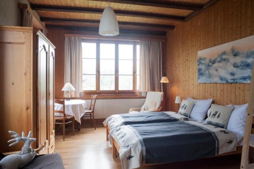 1 dormitorio con cama, mesa y ventana en Hôtel de la Chaux-d'Abel en La Ferrière