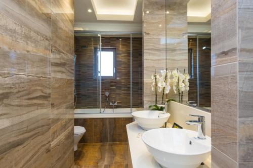 a bathroom with a sink and a toilet and a tub at Aelia Residence, Wellness & Leisure with Heated Pool, By ThinkVilla in Skaleta