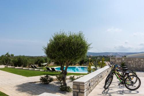 two bikes parked on a wall next to a swimming pool at Aelia Residence, Wellness & Leisure with Heated Pool, By ThinkVilla in Skaleta