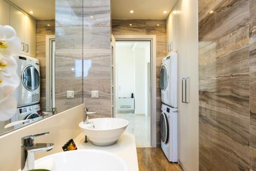 a bathroom with a sink and a washer and dryer at Aelia Residence, Wellness & Leisure with Heated Pool, By ThinkVilla in Skaleta