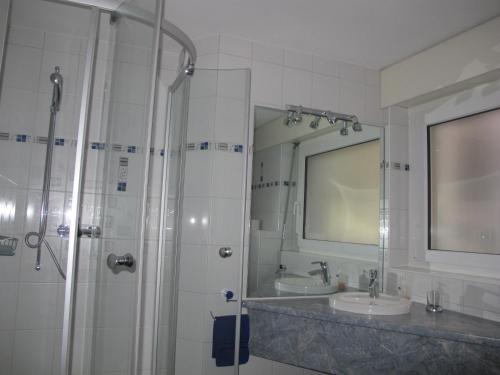 a bathroom with a shower and two sinks and a mirror at Artist Apartments & Hotel Garni in Zermatt