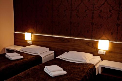 two beds in a hotel room with towels on them at Hotel Serdica in Silistra