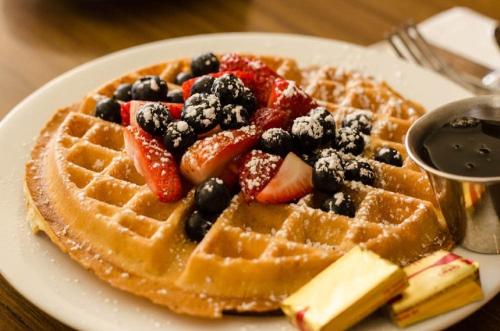 um prato de waffles com morangos e mirtilos em Beverly Laurel Hotel em Los Angeles