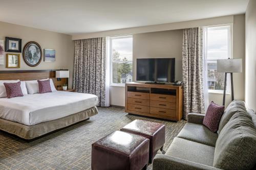 a hotel room with a bed and a couch and a tv at Hotel Madison & Shenandoah Conference Ctr. in Harrisonburg
