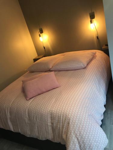 a white bed with a pink pillow on it at Laugann's Home in Cabourg