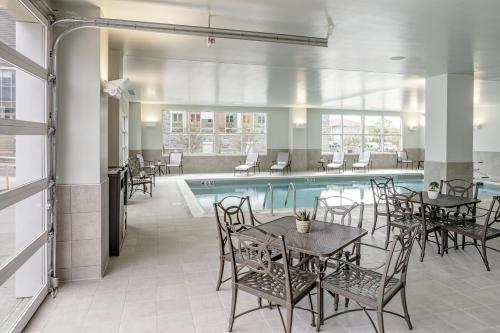 a pool with tables and chairs next to a swimming pool at Hotel Madison & Shenandoah Conference Ctr. in Harrisonburg