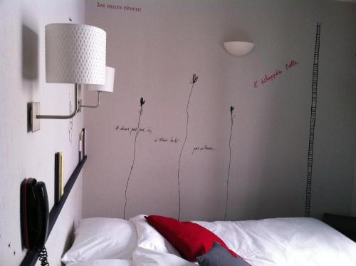 a bedroom with a wall with writing on the wall at Hotel de la Placette Barcelonnette in Barcelonnette