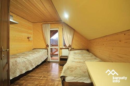 a room with two beds and a table and a window at Nad Cheremoshem in Tyudov