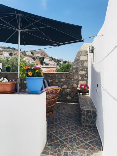 a patio with an umbrella and a bench and flowers at Maria's House in Hydra