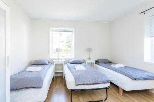 two beds in a white room with two windows at Grand Villa Stavanger in Stavanger
