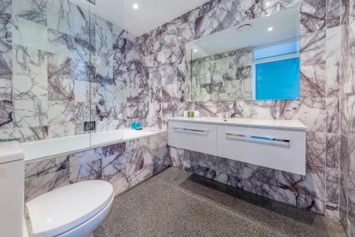 a bathroom with a sink toilet and a mirror at Chic East Sydney Pad in Sydney