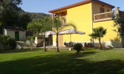 a yellow house with palm trees in a yard at Il Melicucco in Furci Siculo