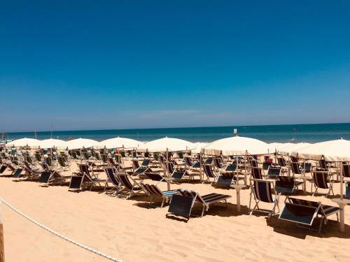 un mucchio di sedie e ombrelloni su una spiaggia di Hotel Corfù a Pineto
