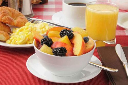 a bowl of fruit on a table with a cup of coffee at Days Inn & Suites by Wyndham Grand Rapids Near Downtown in Grand Rapids