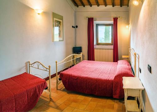 two beds in a room with red sheets and a window at Agriturismo Bagnolo in Pienza