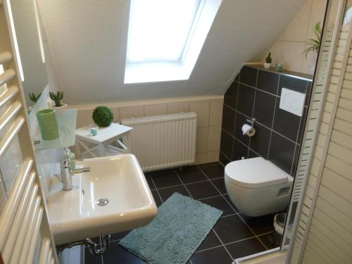 a bathroom with a sink and a toilet and a window at Ferienhaus Neptun in Carolinensiel