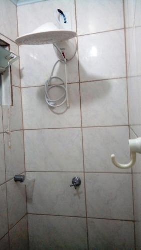 a shower with a white tiled wall and a shelf at Hospedagem 3 Estrelas in Navegantes
