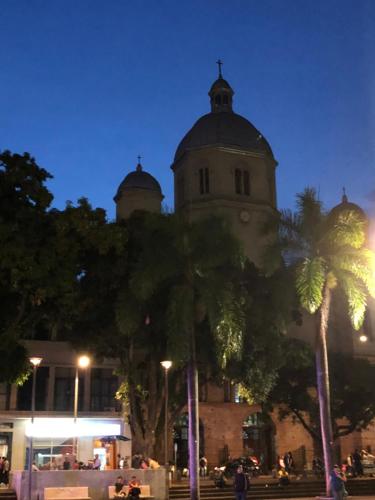 a building with a clock tower with palm trees at night at Hotel Condina Pereira in Pereira