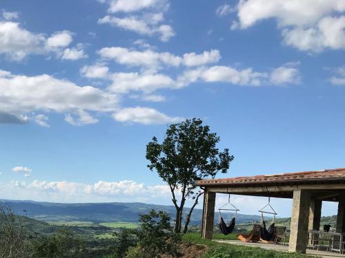 a house with a tree and hammocks on a hill at Villa Podere Del Grasso in Castel del Piano