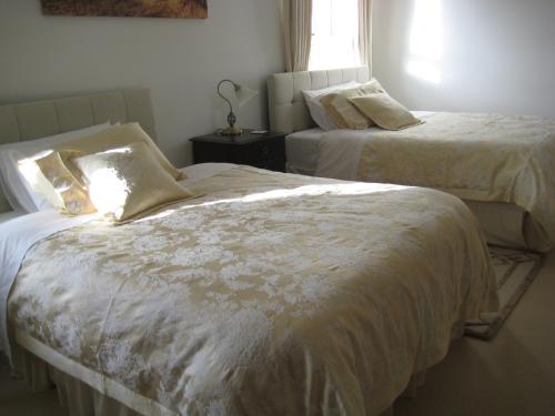 a bedroom with two beds with white sheets and a window at Drumspittal House Guest Accomodation in Armagh