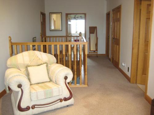 a living room with a chair and a staircase at Drumspittal House Guest Accomodation in Armagh