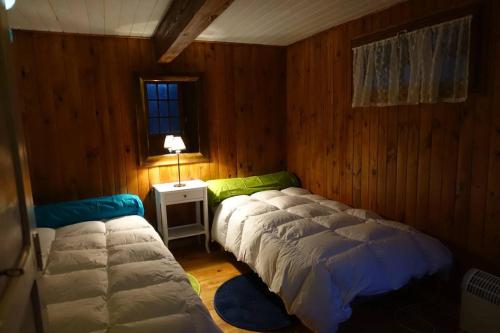 une chambre avec deux lits et une table avec une lampe dans l'établissement Chalet Vintage, à Pollieu