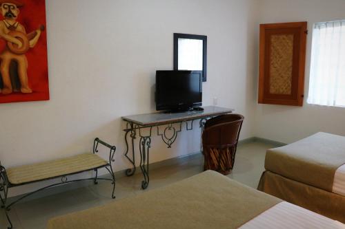 a room with two beds and a table with a television at Zar Colima in Colima