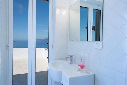 a white bathroom with a sink and a mirror at My Shazzy with amazing Sea View terrace in Praiano