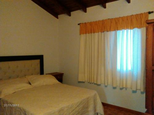 a bedroom with a bed and a window at La Roca Cabañas in Cosquín