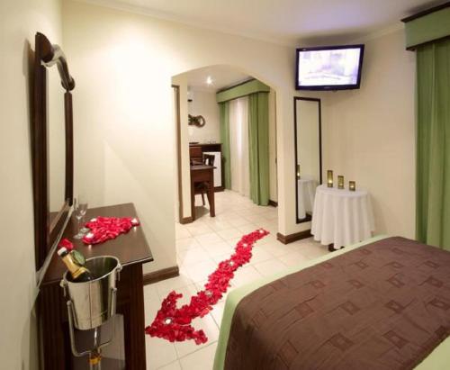 a room with a bed and a table with red flowers on the floor at Hotel Iguana Verde in Orotina