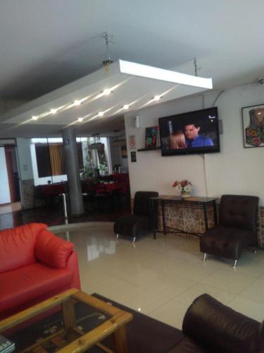 a living room with a red couch and a flat screen tv at CasaHotel Jockey Plaza Mall in Lima