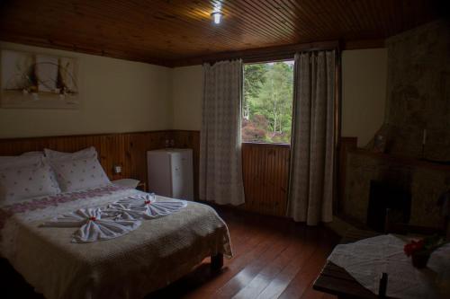 ein Schlafzimmer mit einem Bett und einem großen Fenster in der Unterkunft Pousada da Carmem in Visconde De Maua