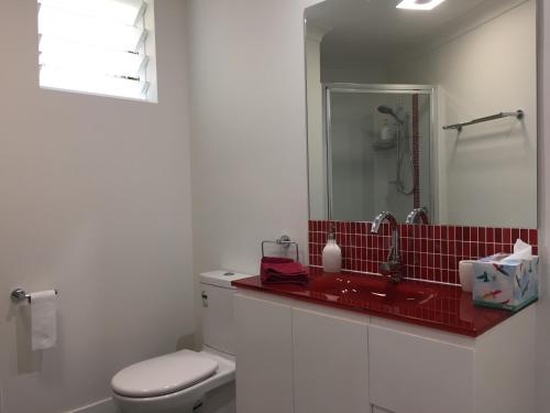 a bathroom with a white toilet and a red sink at Hideaway on Hillview in Cairns