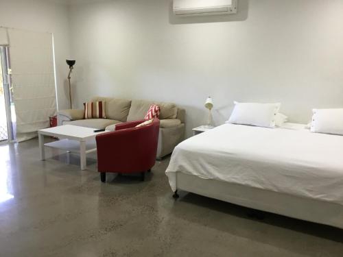 a bedroom with a bed and a couch and a bed and a chair at Hideaway on Hillview in Cairns