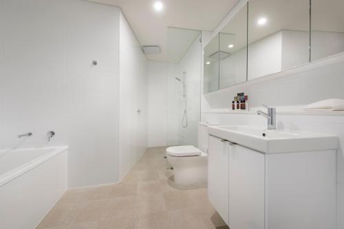 a white bathroom with a sink and a toilet at Ramada by Wyndham VetroBlu Scarborough Beach in Perth