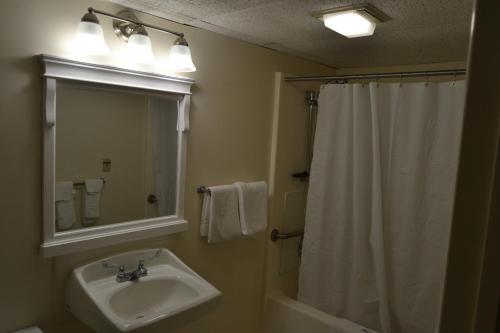 a bathroom with a sink and a shower with a mirror at The Ship Motel in Alexandria Bay