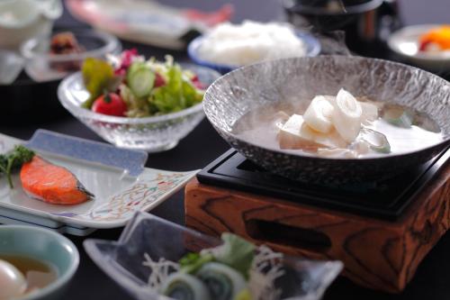 een tafel met een kom soep en borden eten bij Awara Kitagata Onsen Kohanso Hana Yurari in Awara