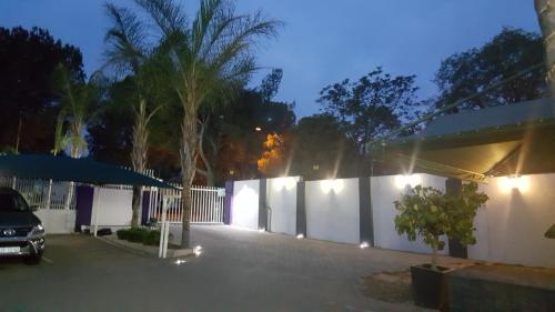 a parking lot in front of a white fence at Lala Dene Lodge in Bloemfontein