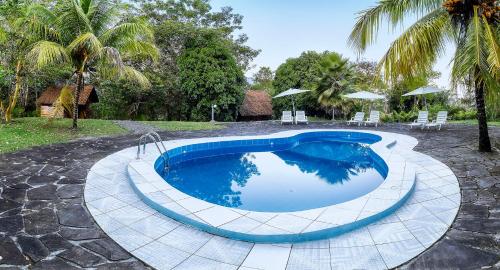 una piscina en un patio con sillas y sombrillas en HuasaiWasi Ecolodge, en Tarapoto