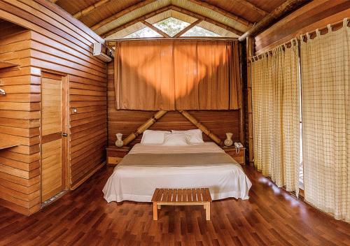 1 dormitorio con 1 cama en una cabaña de madera en HuasaiWasi Ecolodge, en Tarapoto
