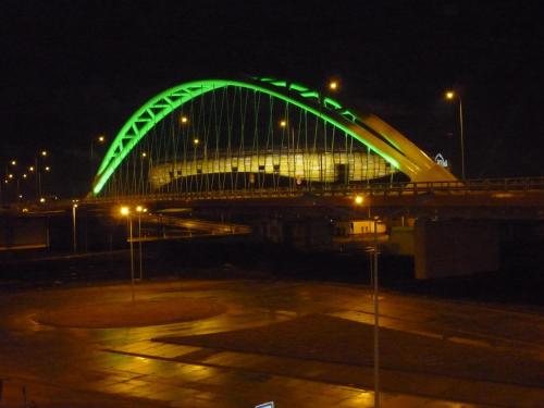Un puente verde frente a un edificio por la noche. en VillaMaria, en Gdansk
