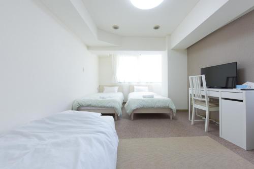 a room with two beds and a desk with a computer at HIROKI Building in Tokyo