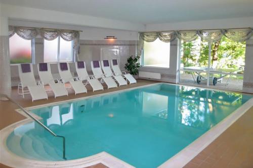 une grande piscine avec des chaises blanches et une piscine dans l'établissement Hotel Birkenhof am See, à Sankt Kanzian