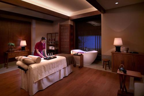 a woman standing in a bathroom with a bed and a bath tub at Jinmao Purelax Lijiang, The Unbound Collection By HYATT in Lijiang