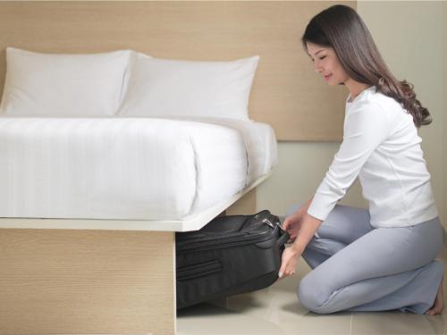 a woman sitting on the floor next to a bed at Hop Inn Hotel Alabang Manila in Manila